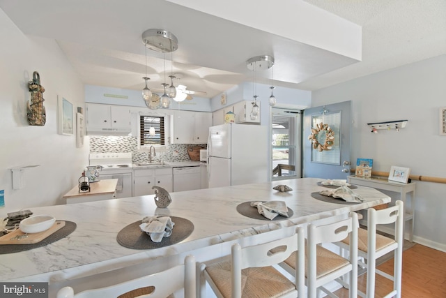 2818 Tern Dr Unit 9, Ocean City, MD 21842 - kitchen featuring backsplash, a breakfast bar area, light wood-style flooring, white appliances, and decorative light fixtures