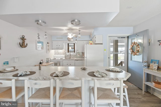 2818 Tern Dr Unit 9, Ocean City, MD 21842 - kitchen featuring a sink, white cabinetry, a breakfast bar, white appliances, and decorative backsplash