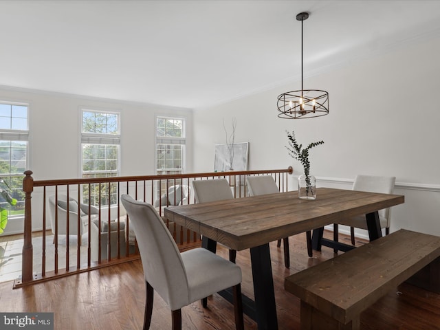 dining space with crown molding, wood finished floors, and an inviting chandelier