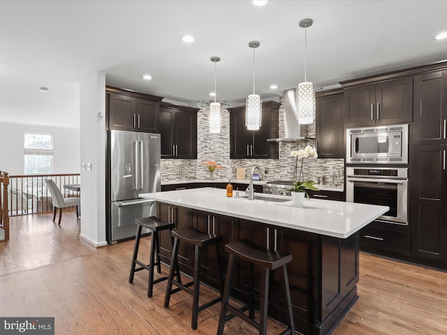 kitchen featuring light countertops, appliances with stainless steel finishes, backsplash, and wall chimney exhaust hood
