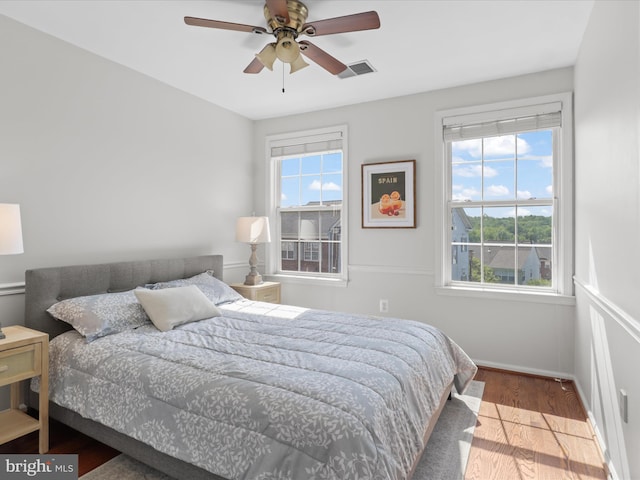 bedroom featuring baseboards, multiple windows, wood finished floors, and visible vents