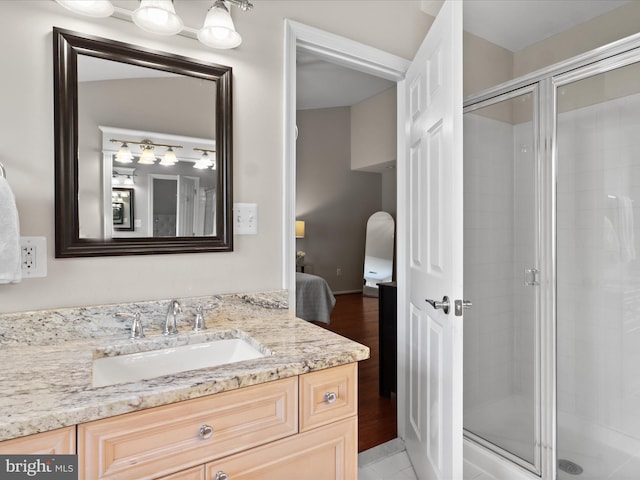 bathroom with vanity, a shower stall, ensuite bath, and wood finished floors