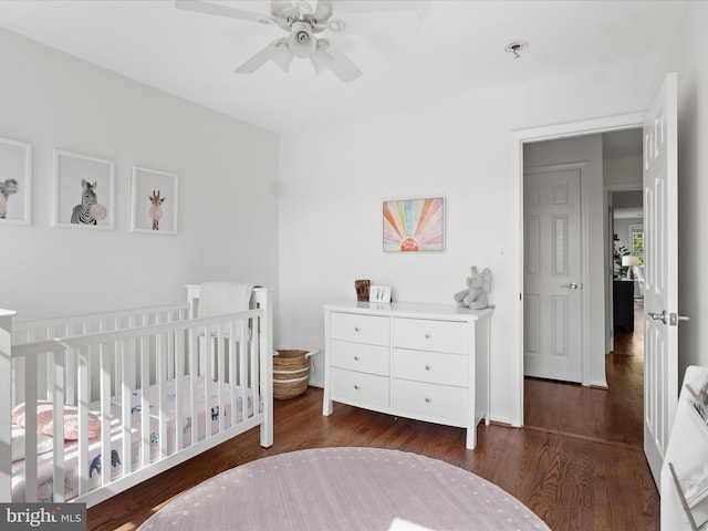 bedroom featuring a crib, ceiling fan, and wood finished floors