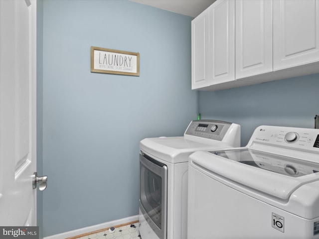 clothes washing area featuring baseboards, cabinet space, and independent washer and dryer