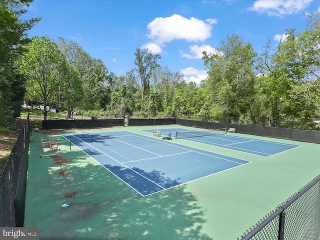 view of tennis court featuring community basketball court and fence