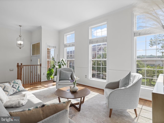 living room with ornamental molding, wood finished floors, and a notable chandelier