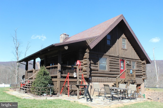 rear view of property featuring log siding and a chimney