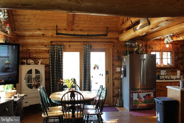 dining space featuring dark wood-style flooring, log walls, and beamed ceiling