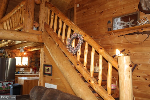 staircase with visible vents, wooden walls, and vaulted ceiling