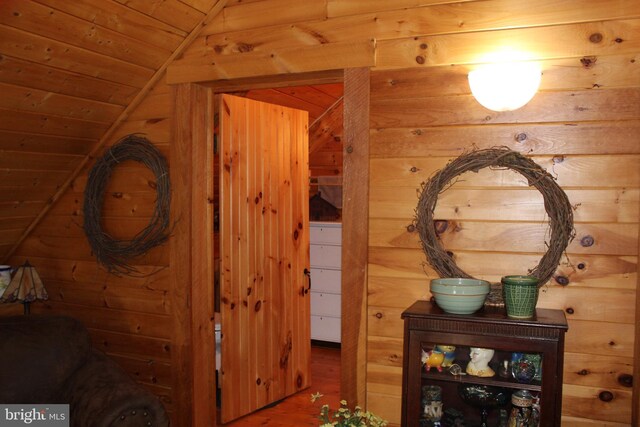 corridor with wooden ceiling, vaulted ceiling, and wooden walls