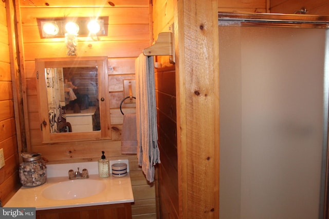 bathroom featuring a shower with shower door, wood walls, and vanity
