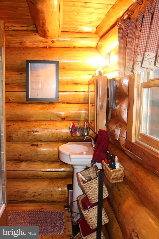 bathroom featuring wood ceiling, a sink, and log walls