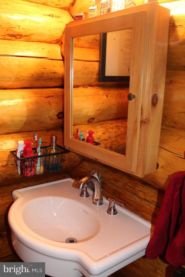 bathroom featuring rustic walls and a sink