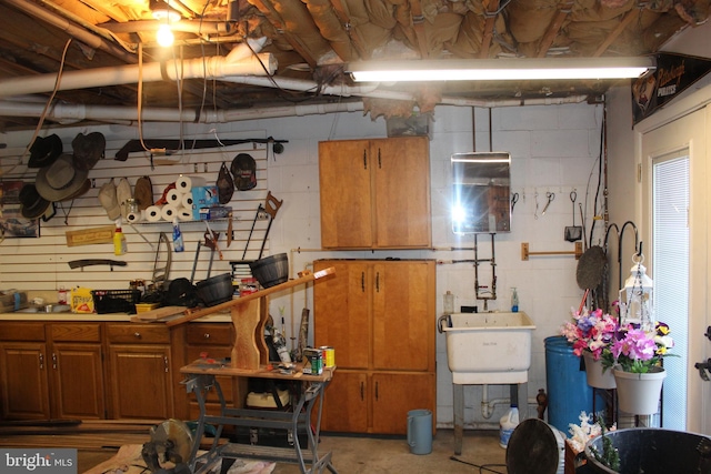 below grade area with a workshop area, concrete block wall, and a sink