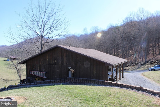 view of pole building with driveway and a yard