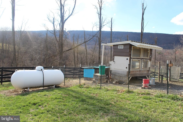 exterior space featuring an outdoor structure, exterior structure, fence, a view of trees, and a lawn