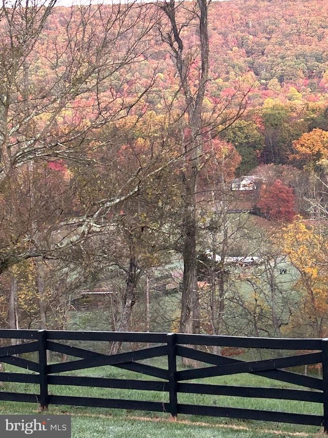view of gate with a view of trees and fence