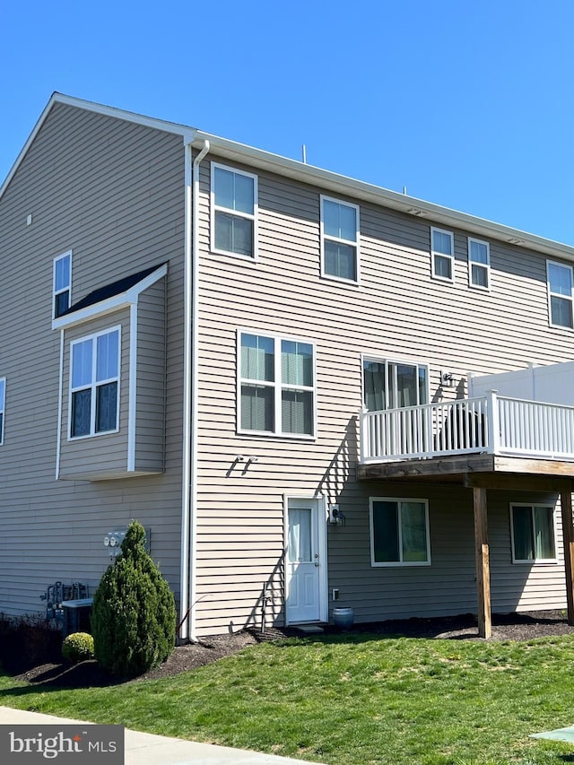 rear view of house with a lawn, a wooden deck, and central AC unit