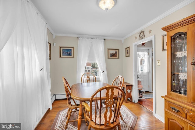 dining area with a wealth of natural light, a baseboard radiator, light wood-type flooring, and ornamental molding