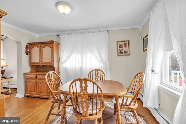 dining space with baseboard heating, crown molding, light wood-style floors, and arched walkways