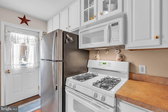 kitchen with glass insert cabinets, white cabinets, light countertops, and white appliances