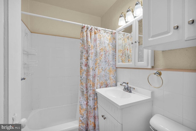 bathroom with toilet, vanity, shower / tub combo, and tile walls