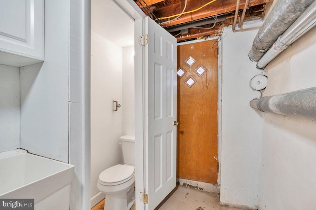 bathroom featuring unfinished concrete floors and toilet