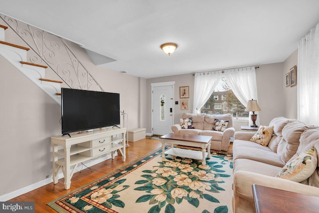 living area with baseboards, wood finished floors, and stairs