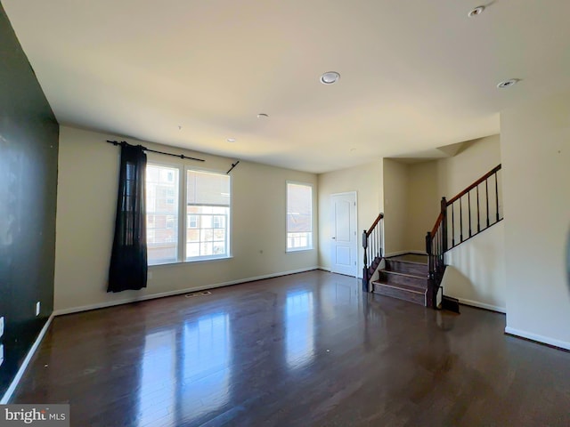 unfurnished living room featuring baseboards, visible vents, wood finished floors, and stairway