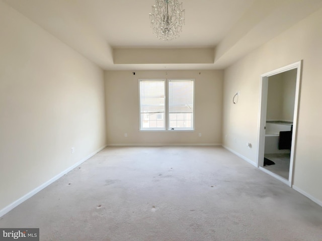 unfurnished bedroom featuring a tray ceiling, baseboards, carpet floors, and an inviting chandelier