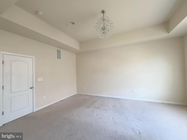 empty room featuring visible vents, baseboards, light carpet, a tray ceiling, and an inviting chandelier