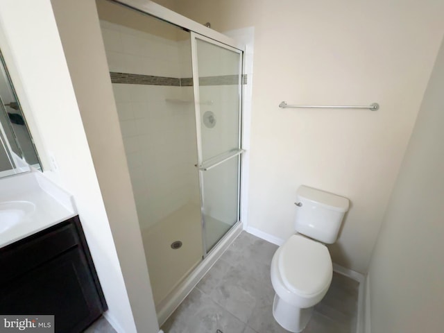 full bathroom featuring a stall shower, baseboards, toilet, and vanity