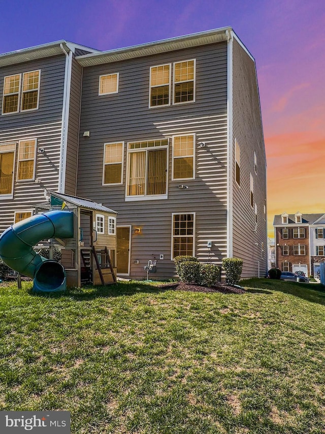 back of property with a playground and a yard