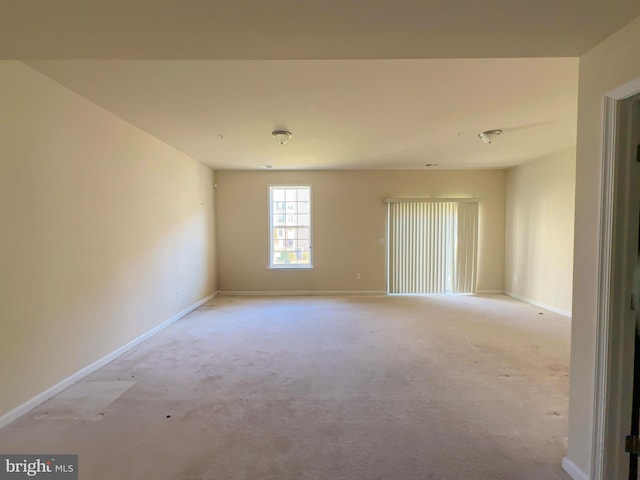 empty room featuring light carpet and baseboards