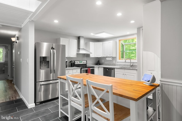 6266 Occoquan Forest Dr, Manassas, VA 20112 - kitchen featuring appliances with stainless steel finishes, wooden counters, wall chimney range hood, a sink, and white cabinets