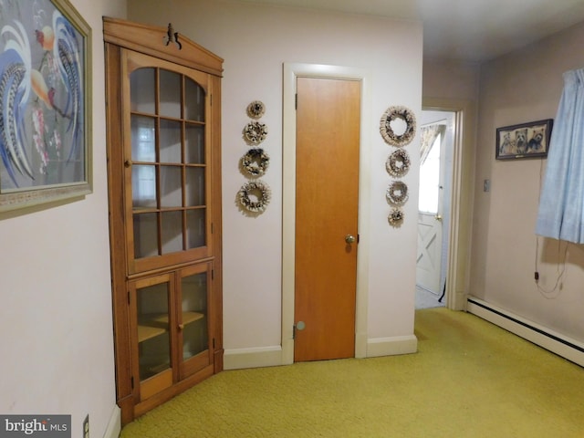interior space featuring a baseboard heating unit, light carpet, and baseboards