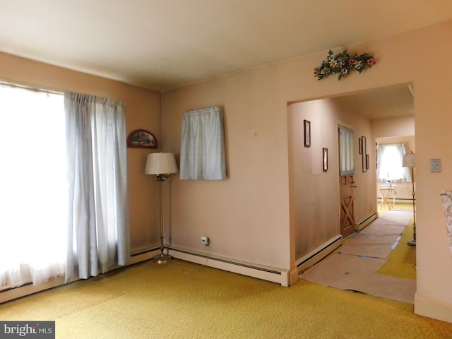 carpeted empty room with a baseboard heating unit