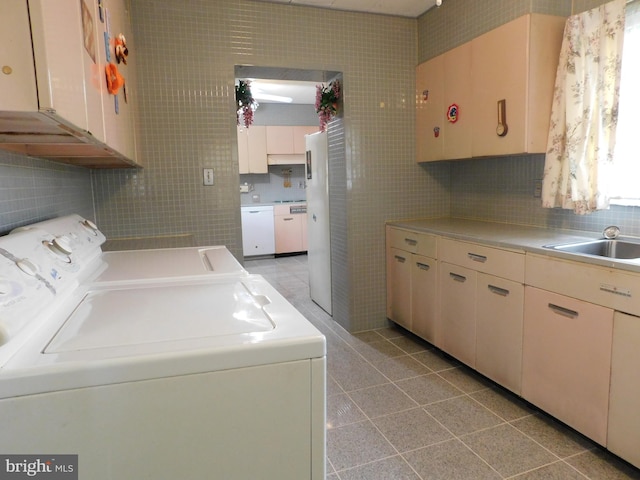 washroom with a sink, light tile patterned flooring, tile walls, cabinet space, and washer and dryer