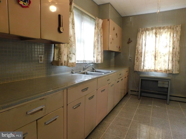 kitchen with baseboard heating, a sink, white cabinetry, and tasteful backsplash