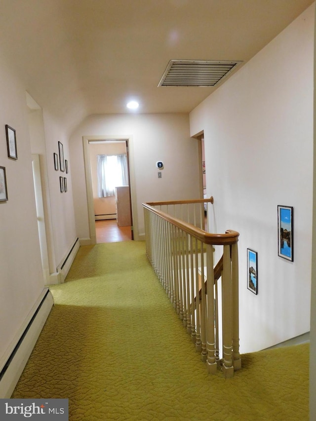hall with a baseboard heating unit, visible vents, carpet flooring, and an upstairs landing