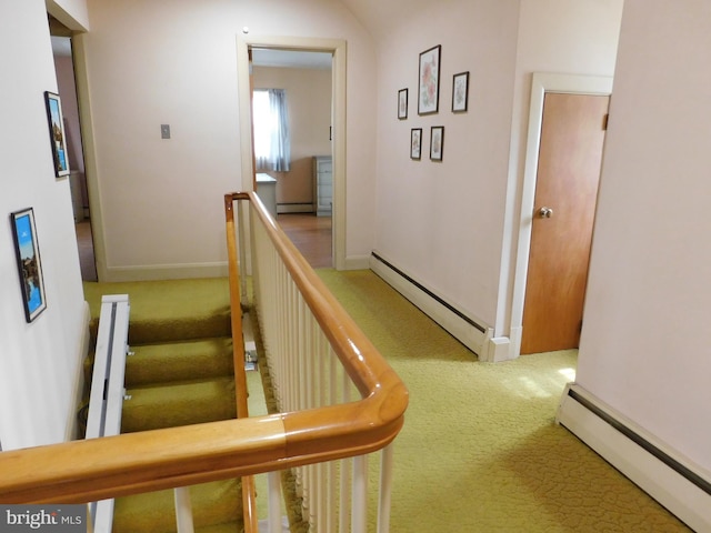 hallway featuring a baseboard heating unit, carpet, and an upstairs landing