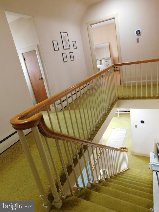 staircase featuring a baseboard heating unit and carpet