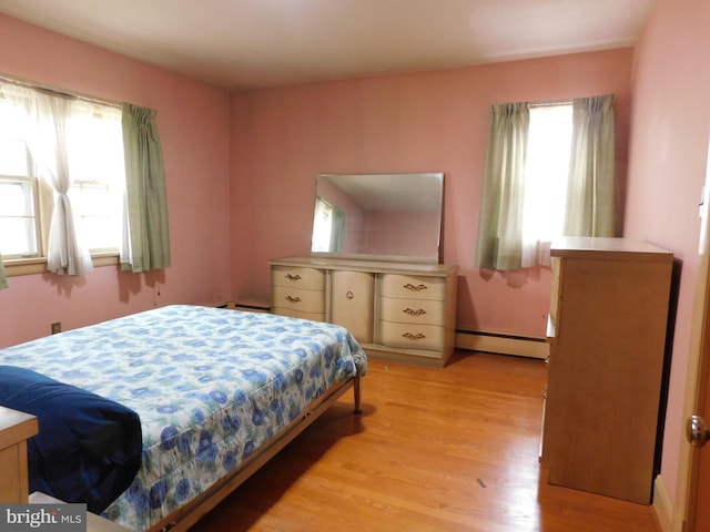 bedroom featuring light wood-type flooring, baseboard heating, and multiple windows