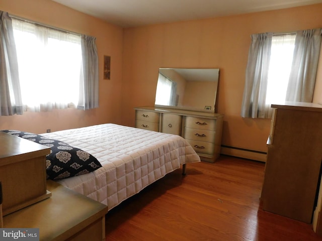 bedroom with a baseboard radiator and wood finished floors