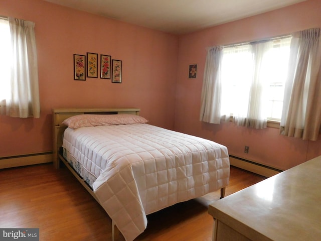 bedroom featuring a baseboard heating unit, a baseboard radiator, and wood finished floors