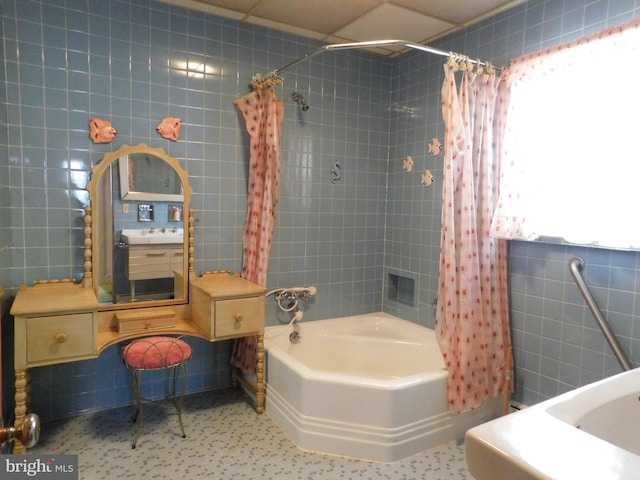 full bath with tile walls, a sink, and shower / bath combination with curtain