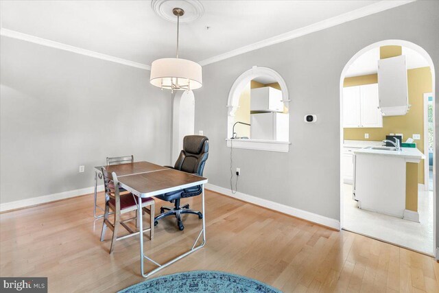 office space featuring baseboards, a sink, light wood finished floors, and ornamental molding