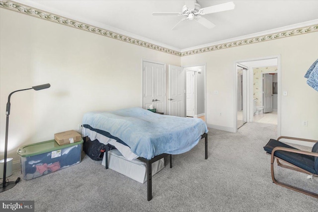 carpeted bedroom featuring connected bathroom, ceiling fan, baseboards, ornamental molding, and a closet