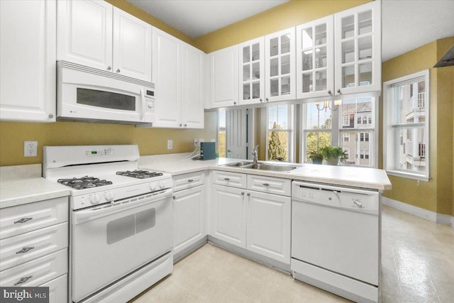 kitchen featuring white appliances, white cabinets, glass insert cabinets, and a sink