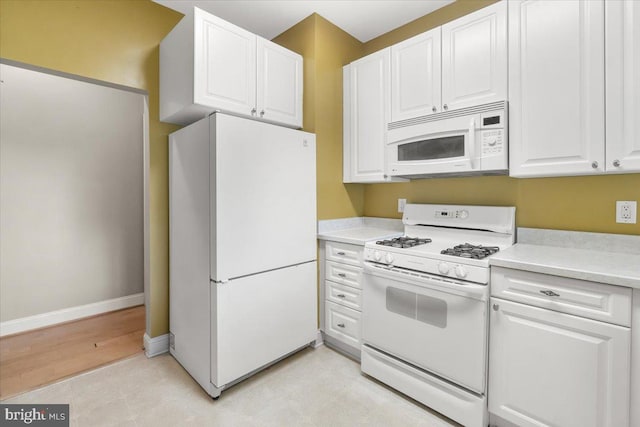kitchen with white appliances, white cabinetry, baseboards, and light countertops